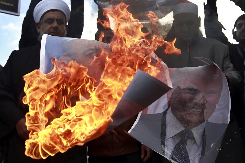 Palestinos queman carteles con retratos del primer ministro israelí Benjamin Netanyahu y el presidente estadounidense Donald Trump, en protesta por la declaración de Trump de reconocer a Jerusalén como capital de Israel, en Ciudad Gaza, jueves 7 de diciembre de 2017. Foto: Khalil Hamra / AP.