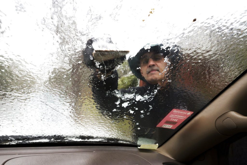 Omar Elkhalidi utiliza un trozo de madera para quitar el hielo acumulado durante la noche en su parabrisas debido a las gélidas temperaturas, el miércoles 3 de enero de 2018. Foto: Stephen B. Morton / AP.