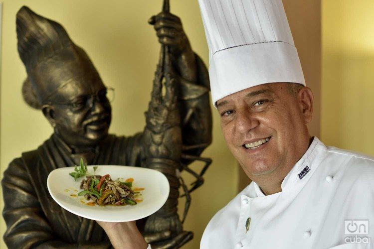 Chef Eddy Fernández, president of the island’s Federation of Culinary Associations and a tireless defender of Cuban cuisine. Behind, a statue of chef Gilberto Smith, founder of the Federation and one of the essential figures of culinary art on the island. Photo: Otmaro Rodríguez.