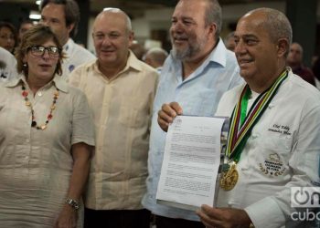 Chef Eddy Fernández (r), president of the Culinary Federation of Cuba, shows the document that accredits Cuban cuisine as national Cultural Heritage. Next to him, Cuban Minister of Tourism Manuel Marrero (second to the right) and Gladys Collazo, president of the National Cultural Heritage Council (l), among other personalities. Photo: Otmaro Rodríguez.