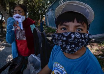 Esperanza Miranda and her grandson wear facemasks to protect themselves from contagion on June 17, 2020 in Immokalee, in South Florida. At the cost of their health, thousands of Mexican and Central American immigrants who are declared “essential” managed to collect this year’s harvest in Immokalee, the tomato capital of the United States and now also one of the hottest spots for the COVID-19 in Florida. Photo: Giorgio Viera/EFE.