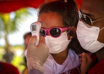 A girl wearing a mask to protect her from the new coronavirus has her temperature taken at a police checkpoint. This was at the entrance to the province of Havana, Cuba, on Monday, August 10, 2020.