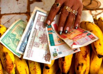 In this file photo, a food vendor distributes convertible pesos and Cuban pesos at her stall in an agricultural market in Havana, Cuba. (AP Photo/Ramón Espinosa).