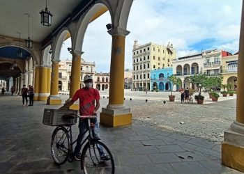 A man with a mask walks his bicycle through a square in Old Havana. Photo: Ernesto Mastrascusa/EFE.