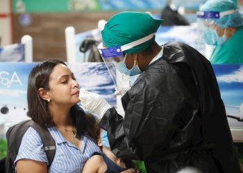 A health worker takes a sample for a PCR test to detect the SARS CoV-2 coronavirus, at the Havana airport after the restart of its regular operations on November 15, 2020. Photo: Yander Zamora/EFE.