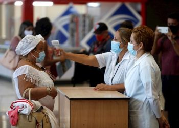 Workers at the Havana airport take the temperature of a female traveler after the restart of
regular operations, suspended for months due to the pandemic. Photo: EFE/Yander
Zamora/Archive.