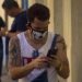 A Cuban man checks his cell phone, wearing a mask in Havana as a protection measure against the COVID-19 pandemic. Photo: Otmaro Rodríguez.