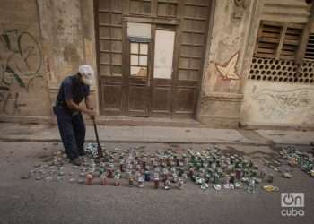 A man crushes soda cans to later sell as raw material. Photo: Otmaro Rodriguez.