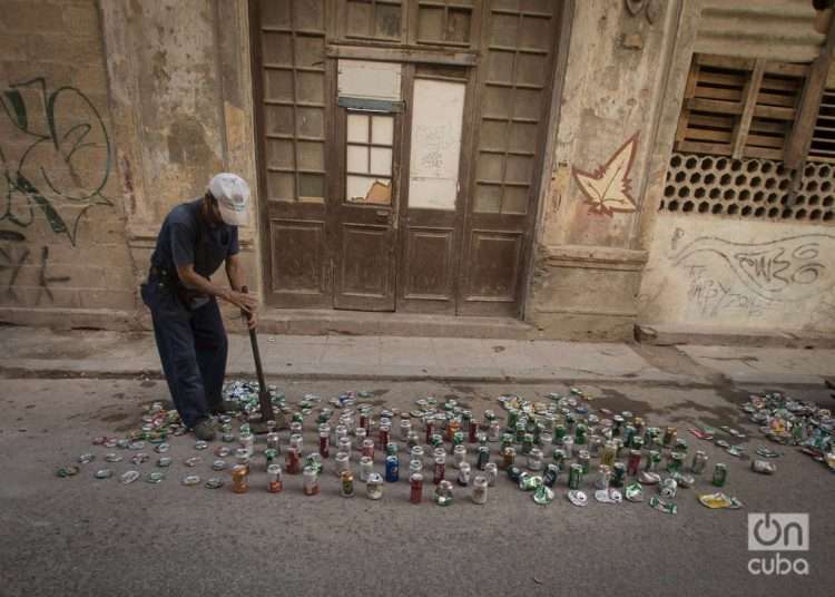 A man crushes soda cans to later sell as raw material. Photo: Otmaro Rodriguez.