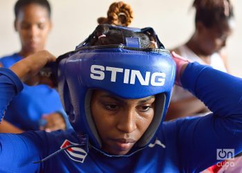 A Cuban woman boxer adjusts her headgear. Cuba