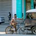 Cyclist holds on to a car so as not to have to force himself to pedal, Havana, Cuba. Photo: Otmaro Rodríguez.