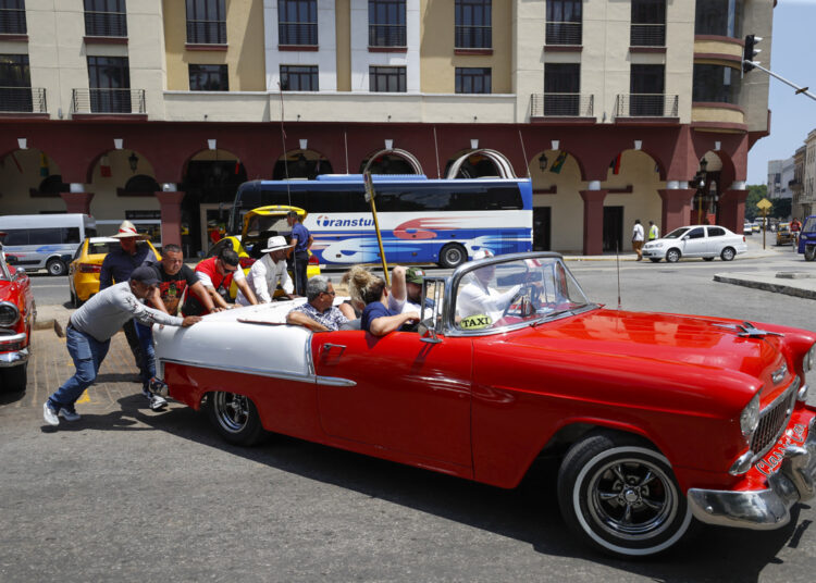 People push a classic car with tourists, in Havana. Photo: Yander Zamora/EFE.