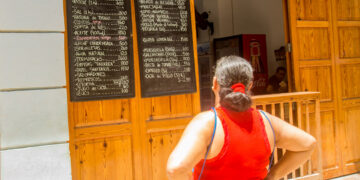 Woman looks at the prices of a MSME in Cuba