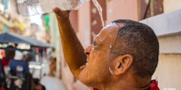 A man splashes himself with water to cool off from the intense summer heat. Photo: Otmaro Rodríguez.