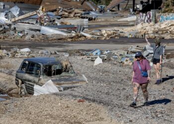 People walking next to a vehicle after the floods caused by Tropical Storm Helene in Asheville, North Carolina. Photo: EFE/EPA Erik S. Lesser.