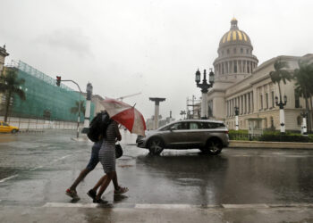 Two people walk in the rain in Havana. Economy