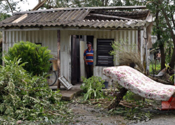 A man observes the roof of his house destroyed after the passage of Hurricane Rafael, in the province of Artemisa. Photo: Ernesto Mastrascusa/EFE.