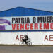 A person rides a bicycle past a sign with the slogan “Patria o Muerte Venceremos” in the city of Cárdenas, Matanzas. Photo: Ernesto Mastrascusa/EFE.