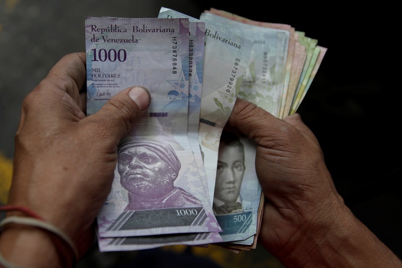 Un trabajador de una gasolinera de PDVSA cuenta bolívares en Caracas. Foto: Marco Bello / Reuters.