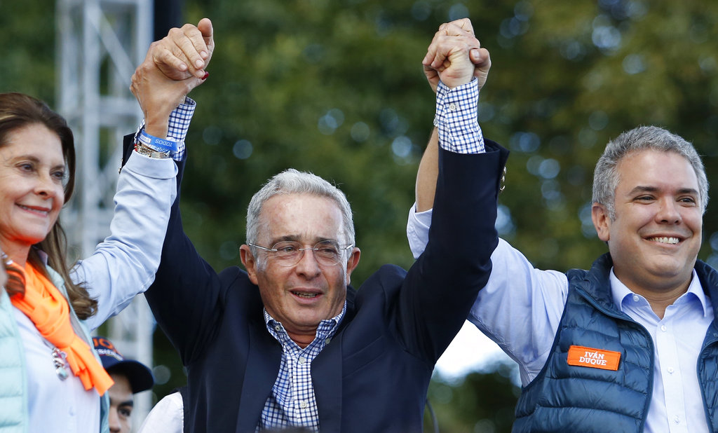 El ex presidente colombiano Álvaro Uribe sonríe entre Iván Duque, aspirante presidencial por el Partido Centro Democrático, derecha, y su compañera de fórmula Martha Lucía Ramírez durante un mítin de campaña en Bogotá, el domingo 20 de mayo de 2018. Foto: Fernando Vergara/AP.