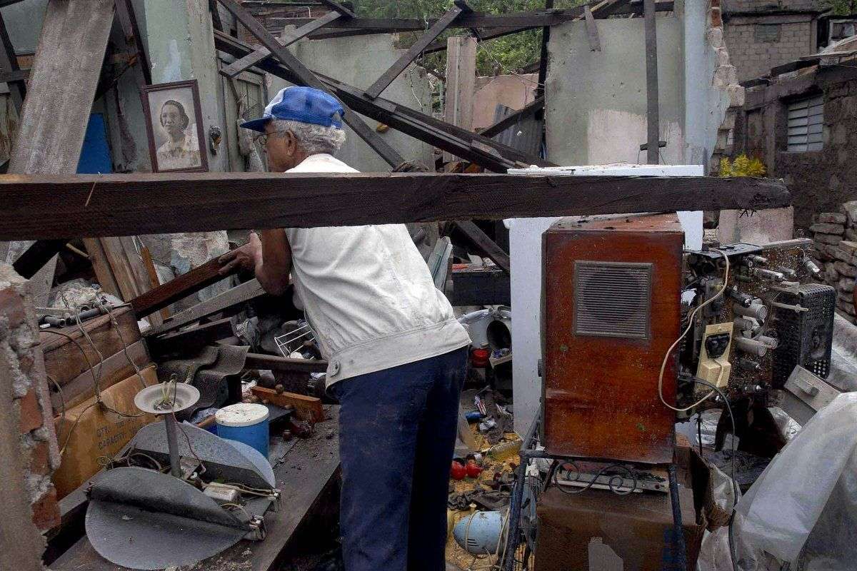 Un hombre ordena lo que le quedó, tras el paso de Sandy por Santiago de Cuba, el 25 de octubre de 2012. Foto: Miguel Rubiera / Reuters.