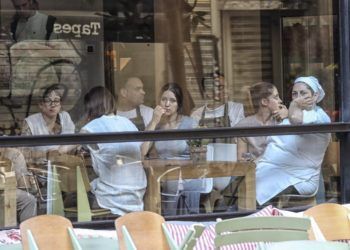 Varias personas esperan en el interior de un bar la autorización de la policía para poder salir.
Foto: Joan Sánchez.