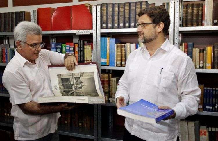 El embajador de España en Cuba, Juan José Buitrago (d), conversa con el director del Instituto de Historia de Cuba, Rene González Barrios (i), en un acto de donación del Instituto de Historia y Cultura Militar del Ejército de España, de 204 libros editados entre 1858 y 2011, dentro de un programa de colaboración que incluye también investigaciones conjuntas sobre la historia compartida entre ambos países. Foto: Ernesto Mastrascusa / EFE.