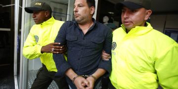 El cubano Raúl Gutiérrez conducido por dos policías tras su detención en Colombia en 2018, acusado de planear acciones terroristas. Foto: Fernando Vergara / AP / Archivo.