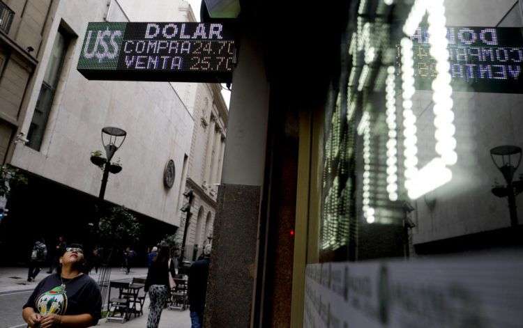 Una mujer observa una pantalla con las tasas de cambio entre el peso argentino y el dólar estadounidense en Buenos Aires, el martes 15 de mayo de 2018. Foto: Natacha Pisarenko / AP.