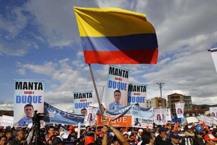 Un simpatizante del candidato presidencial Iván Duque ondea una bandera colombiana durante un evento de campaña en Soacha, a las afueras de Bogotá, el 12 de mayo de 2018. Foto: Fernando Vergara / AP.