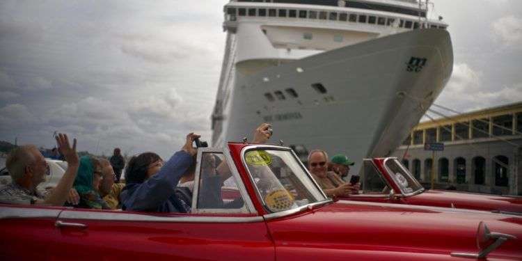 Turistas que recorren La Habana pasan por delante de un crucero atracado en el puerto de la capital de Cuba. Foto: Ramón Espinosa / AP.