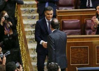 El presidente del gobierno español Mariano Rajoy, de espaldas, estrecha la mano del líder socialista Pedro Sánchez luego de una moción de desconfianza en el paramento en Madrid el viernes, 1ro de junio de 2018. Sánchez fue juramentado el sábado como nuevo jefe del gobierno. Foto: Francisco Seco / AP.