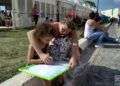 Una madre enseña a su hija a escribir en una pizarra comprada en la Fería del Libro. Foto: Otmaro Rodríguez.