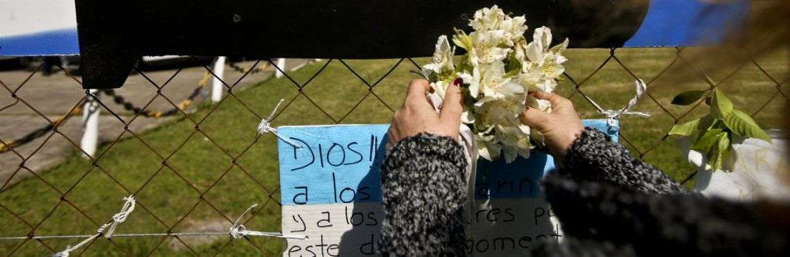 Una mujer coloca flores sobre una imagen recortada del submarino ARA San Juan en la valla de la base naval en Mar de Plata, Argentina. Foto: Esteban Felix / AP.