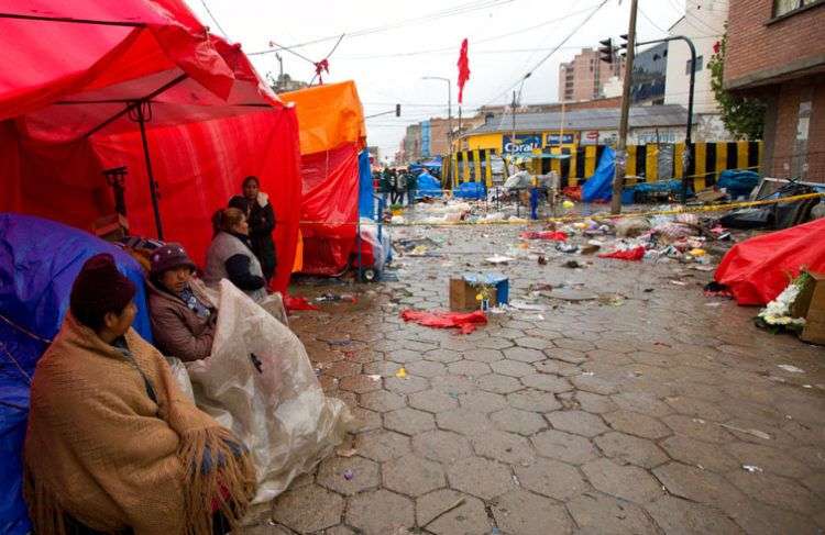 Vendedores callejeros cerca del lugar donde explotó un cilindro de gas en Oruro, Bolivia, que provocó ocho fallecidos y 40 heridos. Foto: Juan Karita / AP.