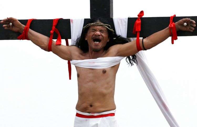 Rubén Enaje gesticula después de haber sido clavado en una cruz por 32º año consecutivo durante una sangrienta representación de los sufrimientos de Jesucristo por el Viernes Santo, que fue vista por miles de espectadores en San Pedro Cutud, Filipinas. Foto: Aaron Favila/AP.