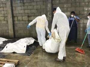 Los trabajadores forenses llevan una lona de plástico que contiene los restos de una víctima del Volcán de Fuego. Foto: Sonia Pérez / AP.