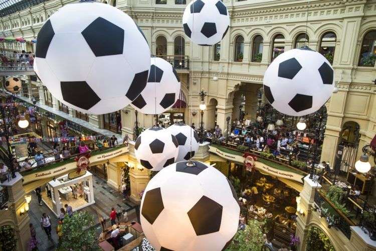 Turistas y aficionados del fútbol caminan por el centro comercial GUM decorado con enormes balones de fútbol con motivo del Mundial en Moscú, Rusia. Foto: Alexander Zemlianichenko/AP.