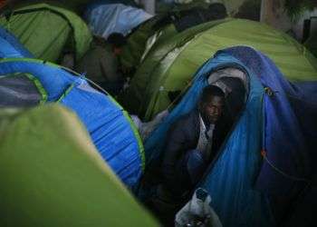 Un inmigrante espera junto a su tienda de campaña durante el desalojo de un asentamiento improvisado en París, el 30 de mayo de 2018. Foto: Thibault Camus/AP.