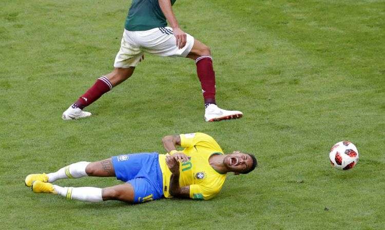 El delantero de Brasil Neymar en el piso ante el defensor de México Edson Álvarez en el partido de octavos de final del Mundial en Samara, Rusia, el lunes 2 de julio de 2018. Foto: Sergei Grits / AP.