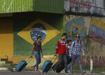 Venezolanos avanzan con su equipaje tras cruzar la frontera entre Brasil y Venezuela en la ciudad de Pacaraima, estado brasileño de Roraima, en marzo de 2018. Foto: Eraldo Peres / AP.