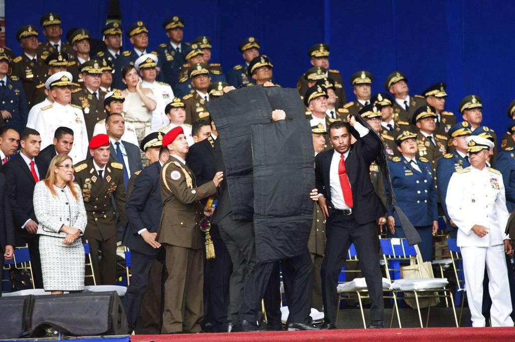 En esta fotografía facilitada por la Agencia de Noticias Xinhua de China, personal de seguridad protege de inmediato al presidente Nicolás Maduro, Al centro, durante un incidente ocurrido cuando pronunciaba un discurso en Caracas, el sábado 4 de agosto de 2018. Según las autoridades, drones cargados con explosivos estallaron cerca de donde se encontraba el mandatario socialista, que resultó ileso aunque siete personas resultaron heridas. (Xinhua vía AP)