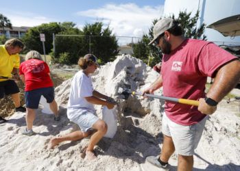 Walker Townsend (derecha), de Isle of Palms, en Carolina del Sur, llena un saco de arena que sostiene Dalton Trout, en un estacionamiento municipal donde se reparte arena de forma gratuita dentro de los preparativos para la llegada del huracán Florence a la región. Foto: Mic Smith / AP.