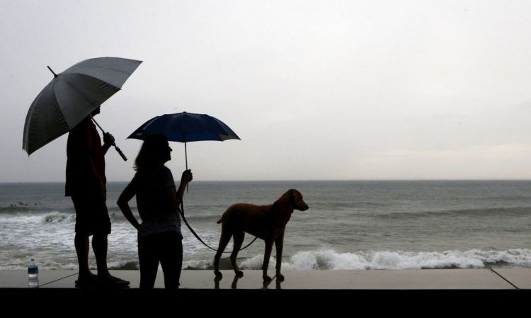 Una pareja y su perro, parados en la orilla antes de la llegada del huracán Willa, en Mazatlan, México, el 23 de octubre de 2018. Foto: Marco Ugarte / AP.