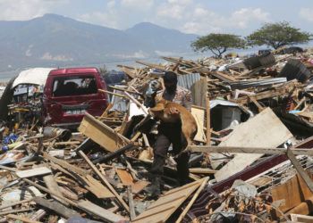 Un agente de policía carga con un perro rastreador de la unidad K9 durante la operación de búsqueda de víctimas del terremoto y tsunami en Palu, en la isla indonesia de Célebes, el 3 de octubre de 2018. Foto: Tatan Syuflana / AP.