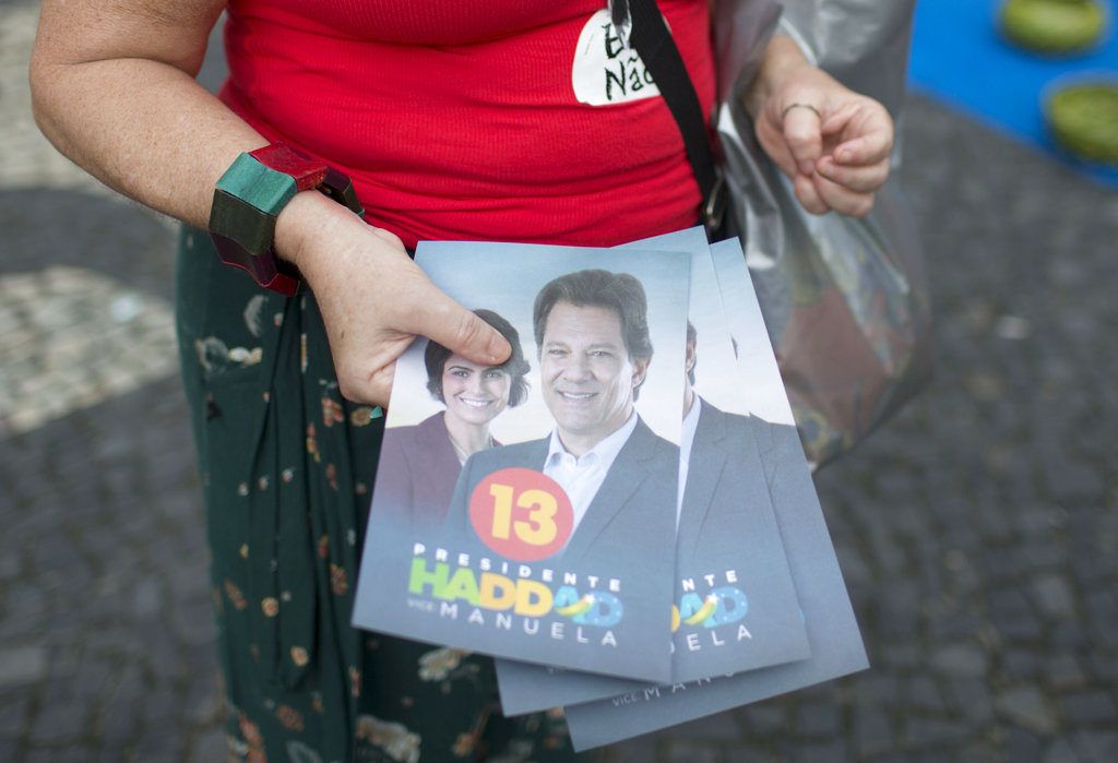 En esta imagen del 17 de octubre, una voluntaria de campaña sostiene volantes a favor del candidato del Partido de los Trabajadores, Fernando Haddad, y utiliza una calcomanía con la leyenda #ElNo en contra del candidato de extrema derecha, Jair Bolsonaro, en Río de Janeiro, Brasil. Foto: Beatrice Christofaro / AP.