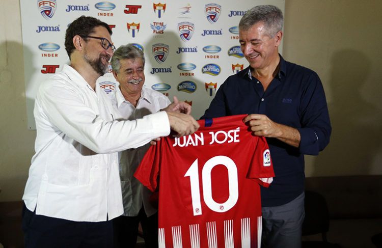 El consejero delegado del Club Atlético de Madrid, Miguel Ángel Gil Marín (d), entrega una camiseta del Club al embajador de España en Cuba, Juan Jose Buitrago (i), junto al comisionado nacional de Fútbol en Cuba, Luis Hernández (c), este martes 2 de octubre de 2018, en La Habana. Foto: Ernesto Mastrascusa / EFE.