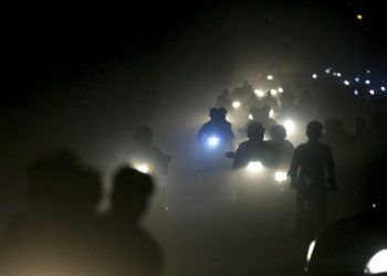 Motociclistas indios atraviesan una espesa nube de smog y polvo en las afueras de Nueva Delhi. Foto: Altaf Qadri / AP.