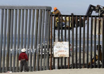 Un hombre en el lado estadounidense de la frontera (arriba) trabaja en la estructura ante la mirada de otro desde la playa, en Tijuana, México, el 15 de noviembre de 2018. (AP Foto/Gregory Bull)