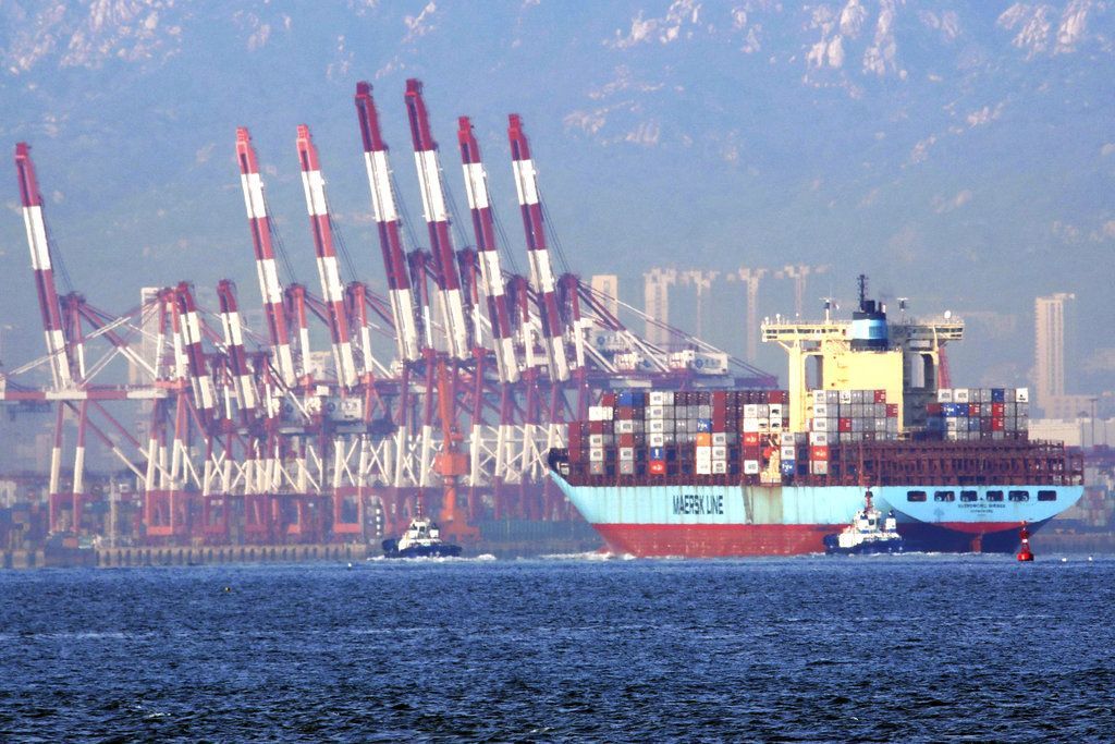 En esta imagen, tomada el 8 de octubre de 2018, remolcadores mueven un barco con contenedores en el puerto de Qingdao, en la provincia de Shandong, en el este de China. (Chinatopix via AP)